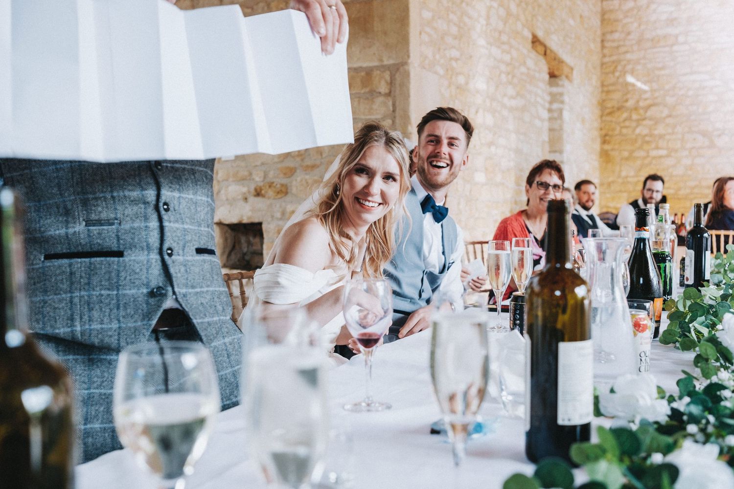 Wedding reception scene with tables decorated with wine glasses and floral arrangements during celebratory toasts.