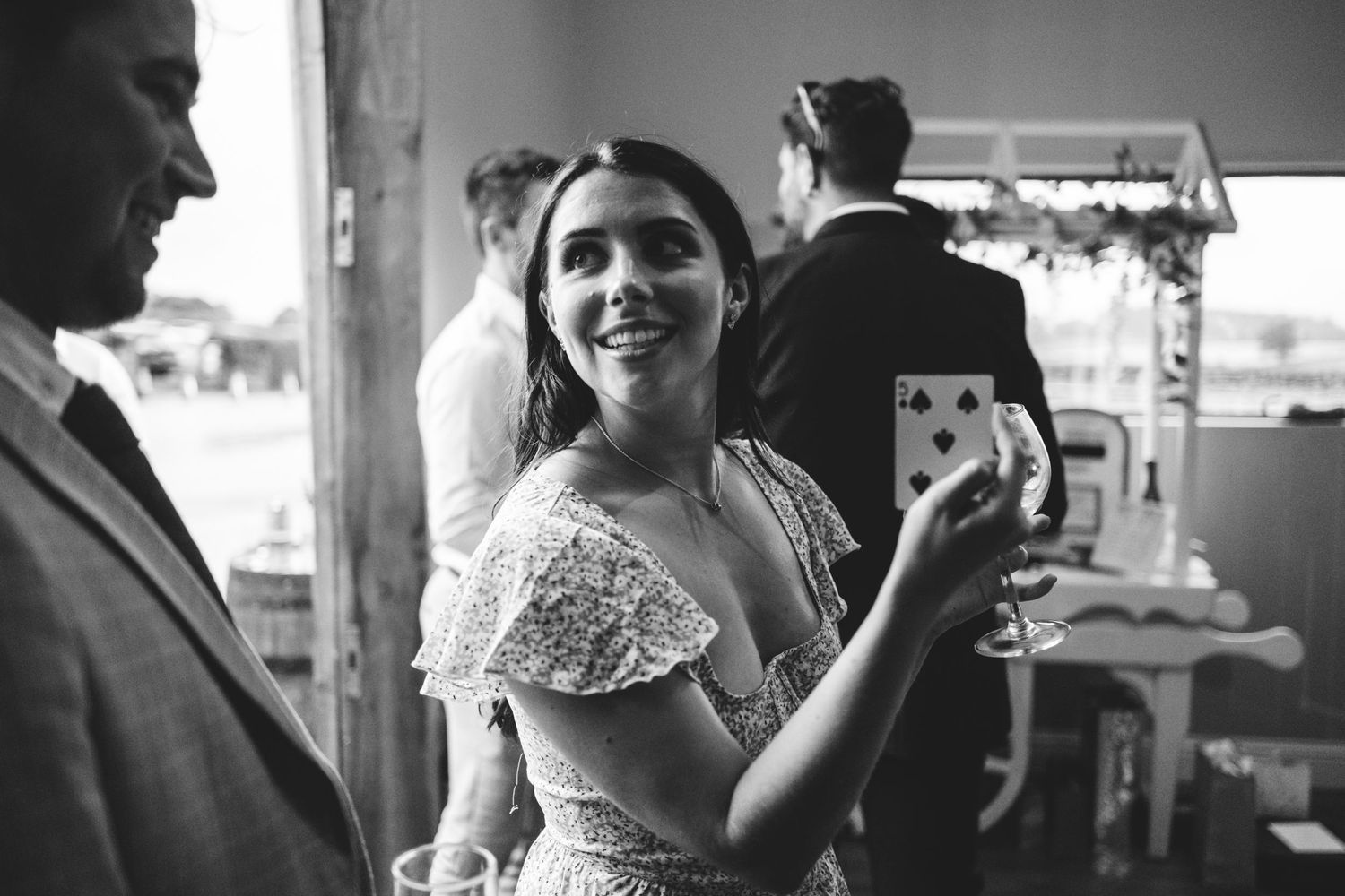 A black and white candid photo showing a joyful moment at an elegant celebration with wine and laughter.