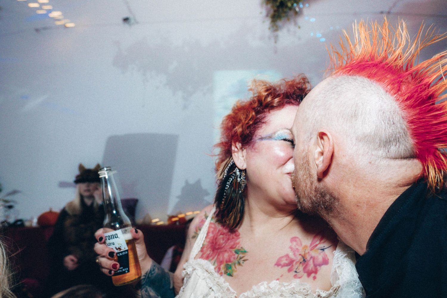 Alternative wedding couple with bright pink hair sharing an intimate moment at their reception.