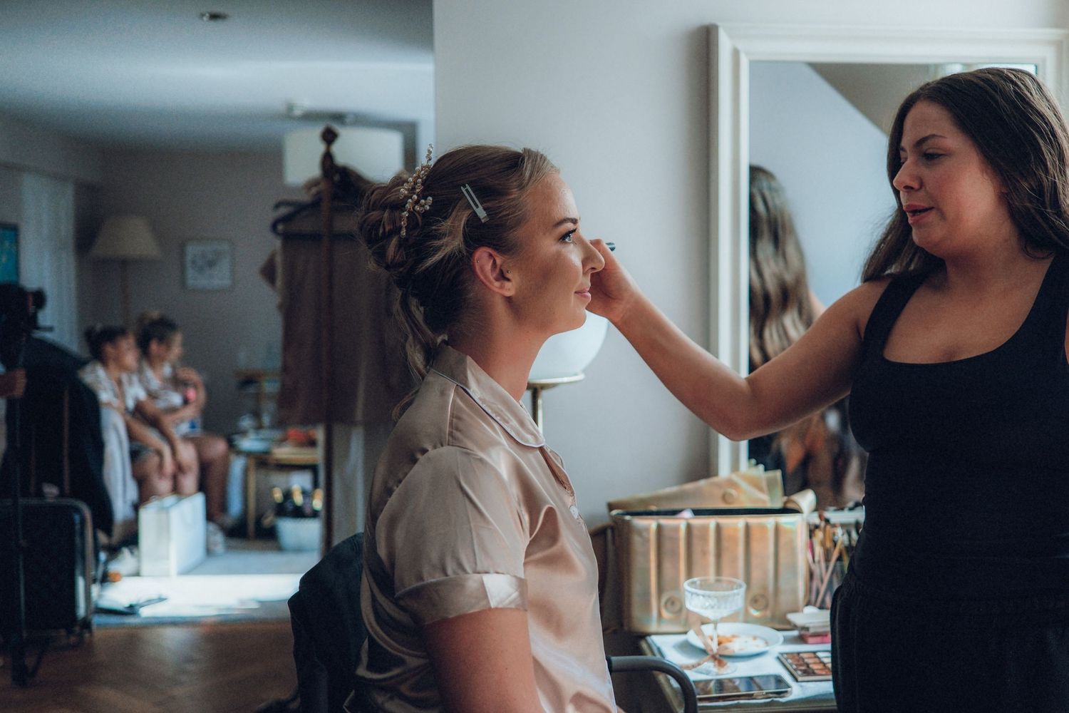 A makeup artist works on wedding day preparations in a bright room.