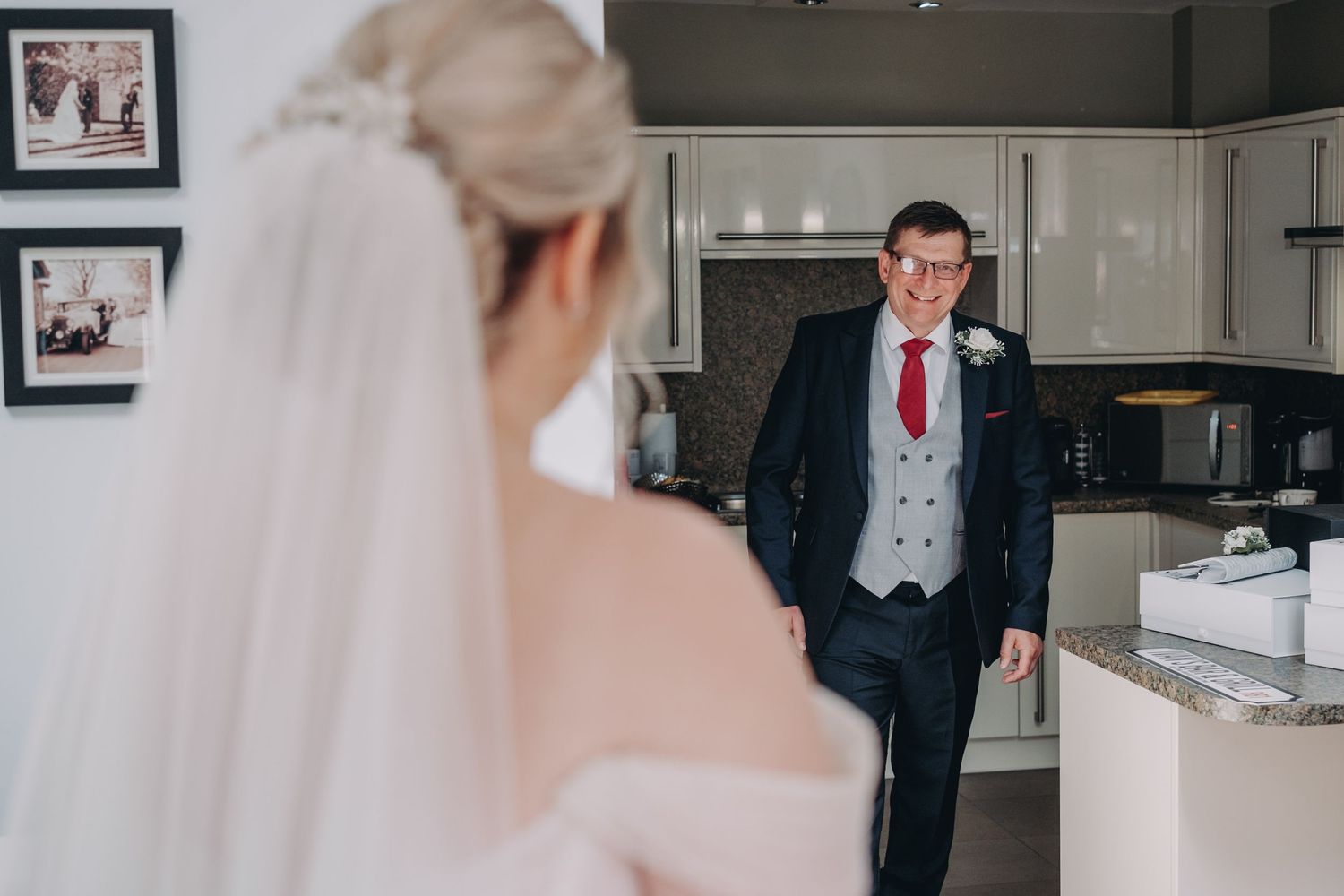 First look moment captured in a modern kitchen setting during wedding preparations.