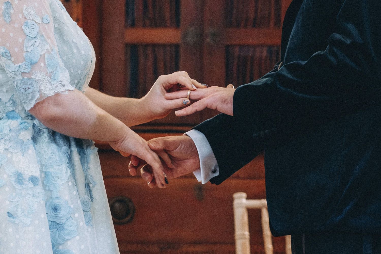 A close-up shot of hands exchanging rings during a wedding ceremony.