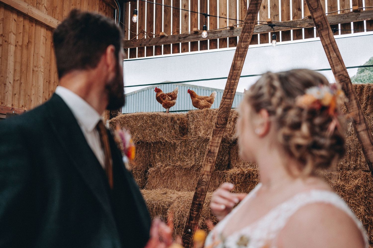 Rustic barn wedding scene with hay bales and wooden beams.