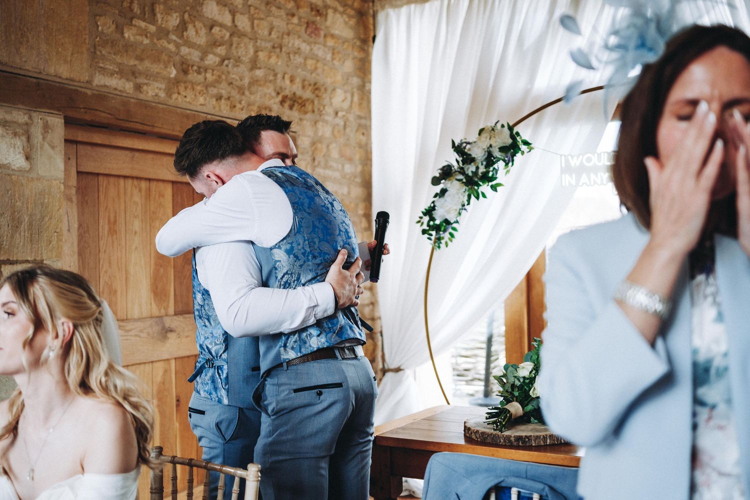 Emotional reactions during wedding speeches at stone-walled reception venue.