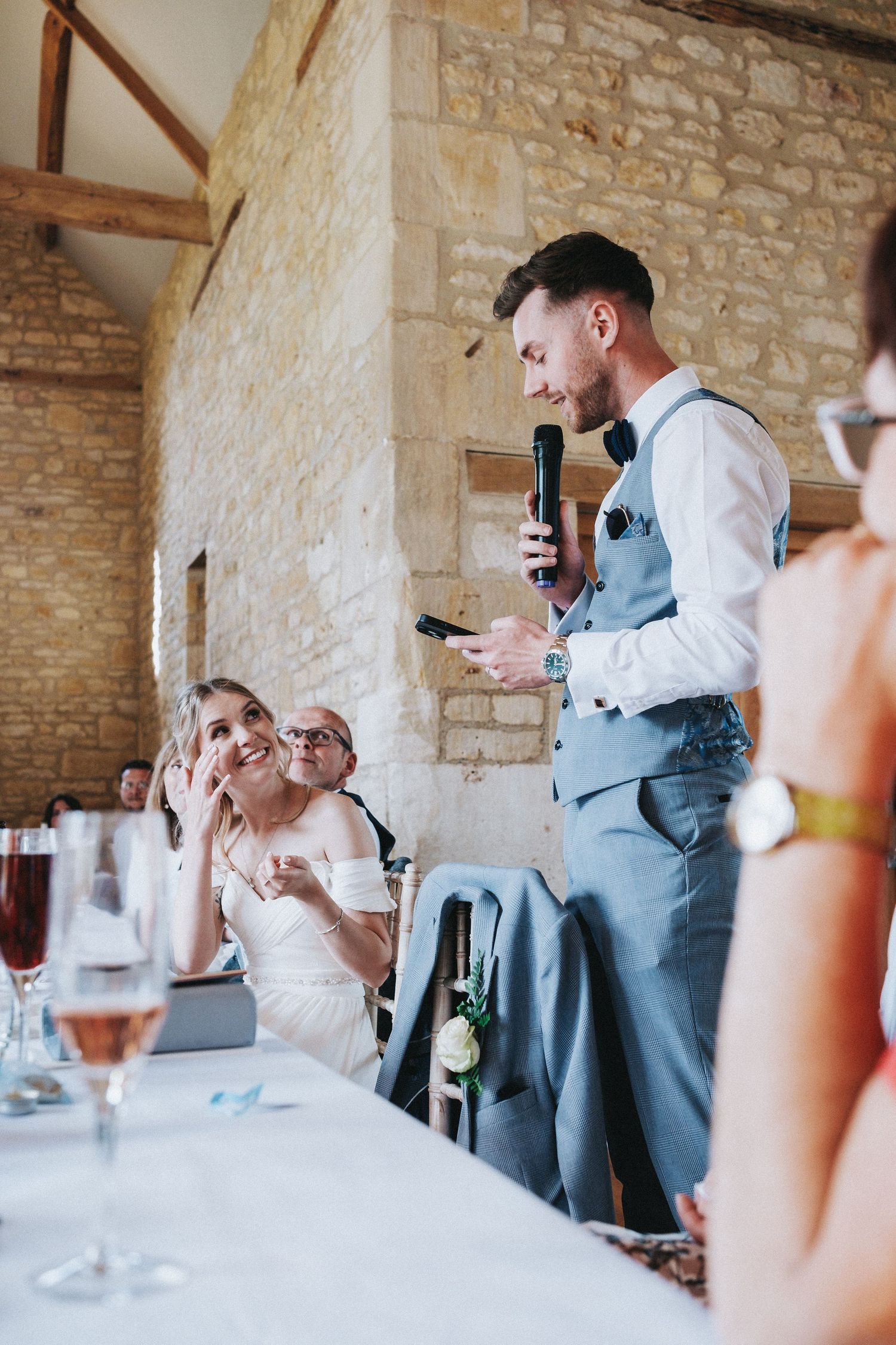 Wedding speeches and toasts being given in elegant stone barn venue.