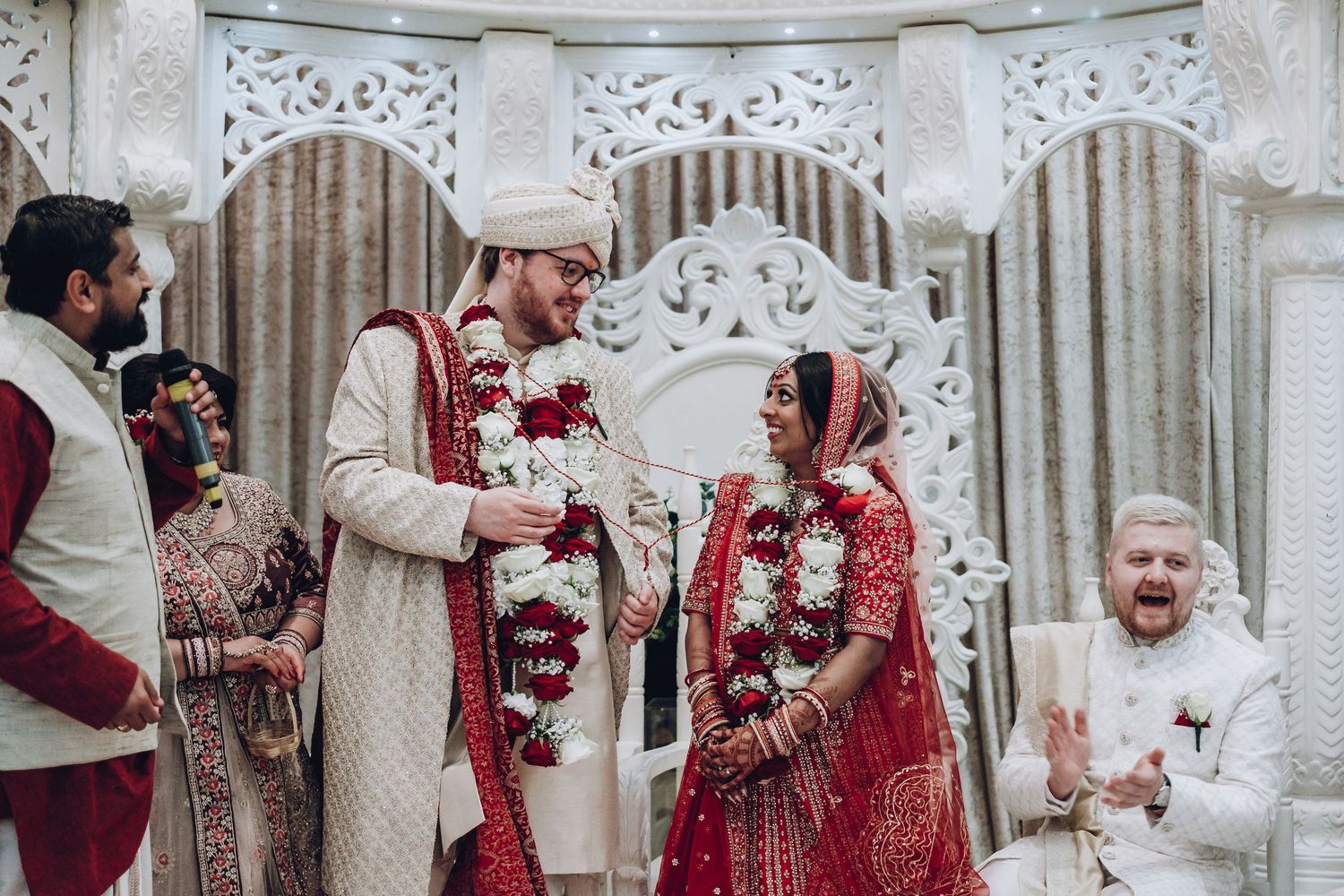 Traditional South Asian wedding ceremony with elegant decor and ornate details in white and red color scheme.