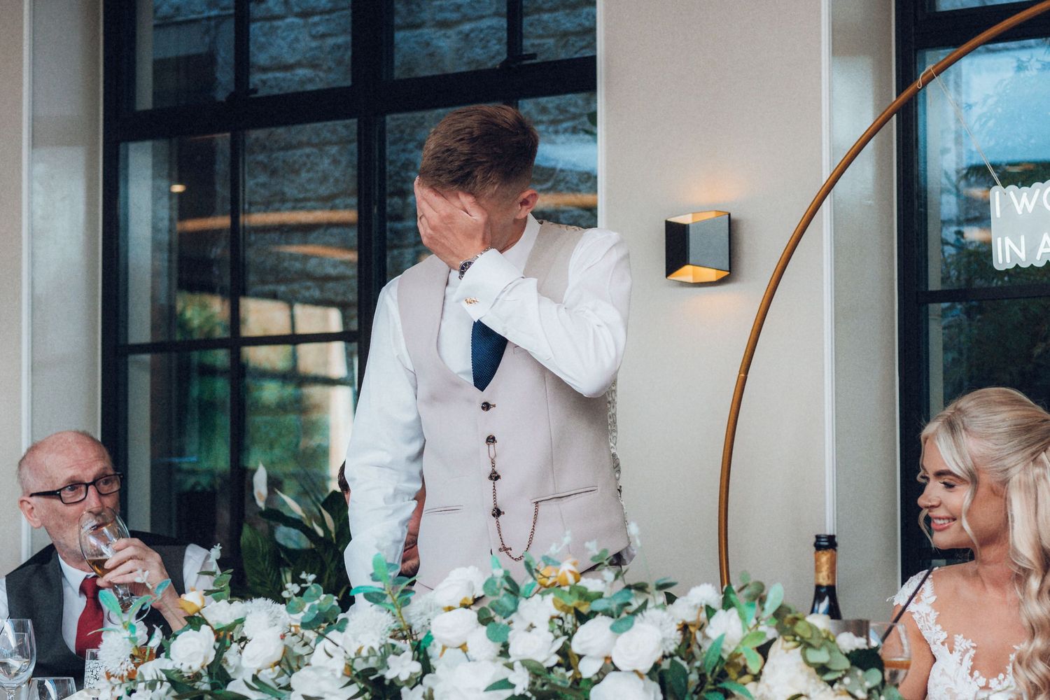 Wedding reception venue decorated with white florals and modern lighting.