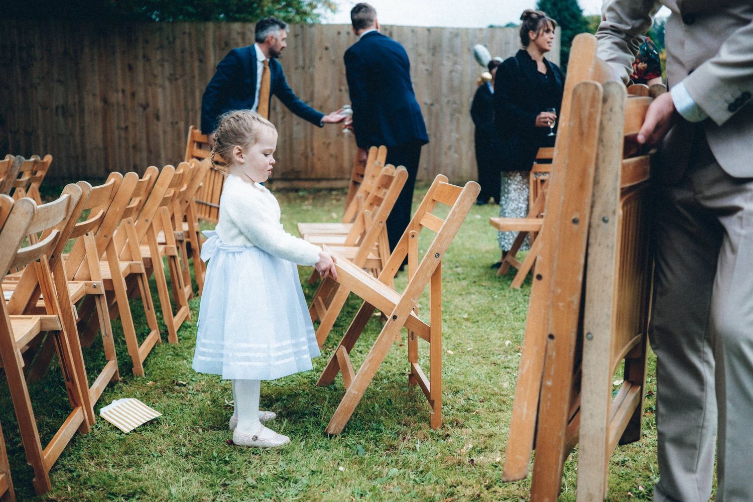Wooden folding chairs set up on grass for an outdoor wedding ceremony.