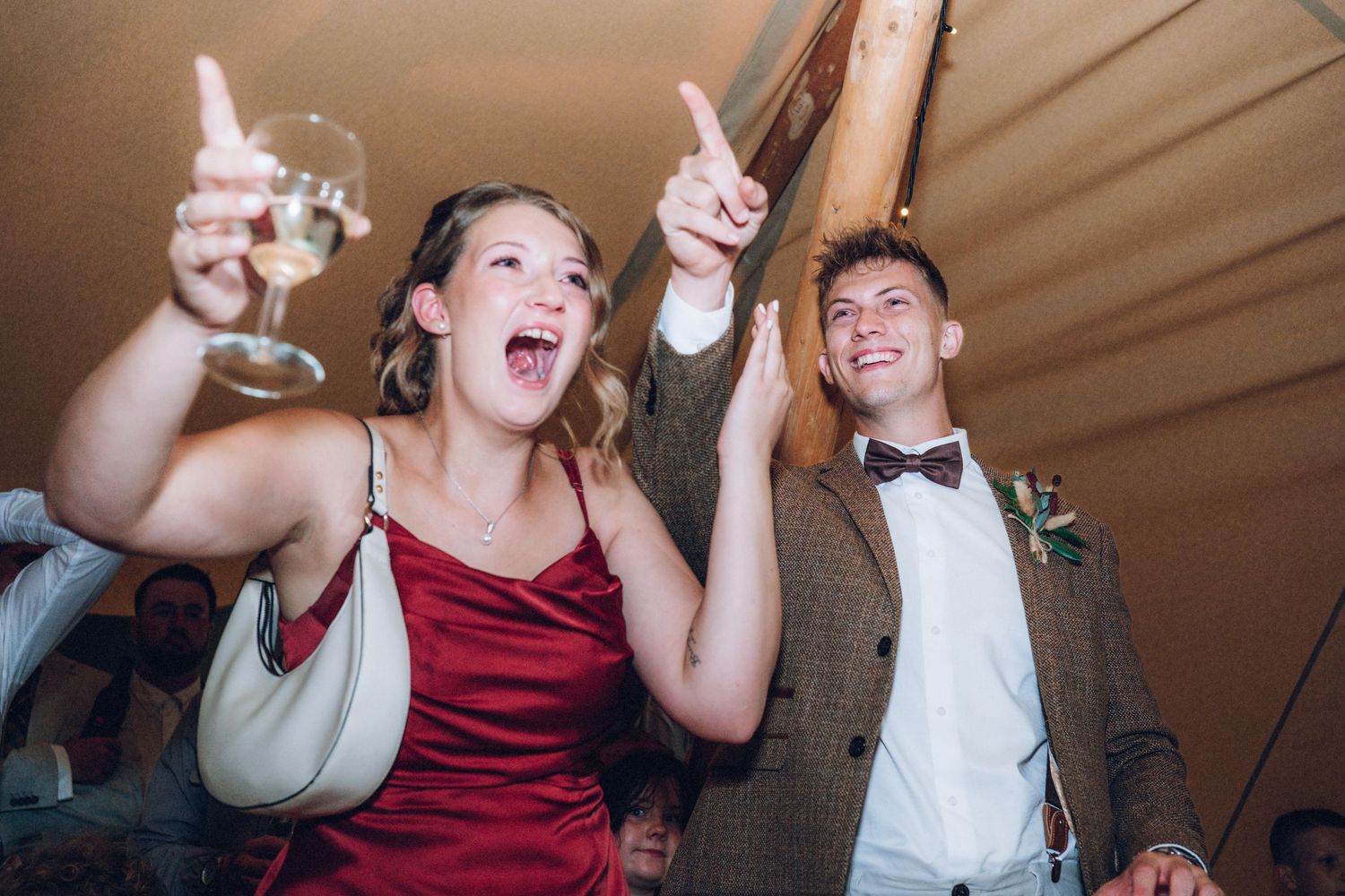 Celebration under a tent with people dancing and enjoying festive moments.