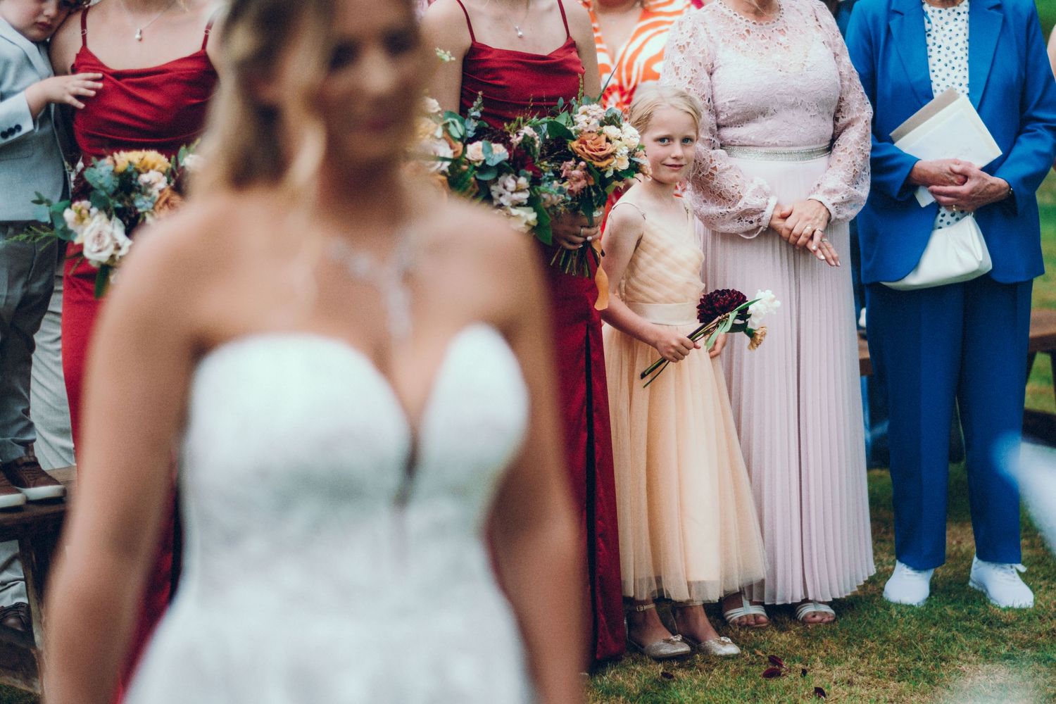Wedding group photo showing bridal party members in red dresses and formal attire.