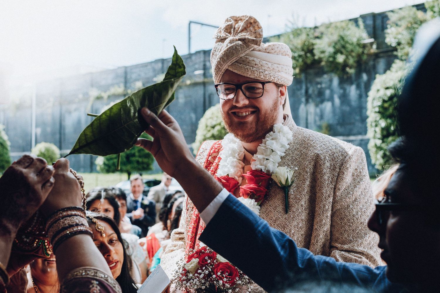 Joyful celebration at a traditional Indian wedding ceremony with vibrant red flowers and decorative attire.