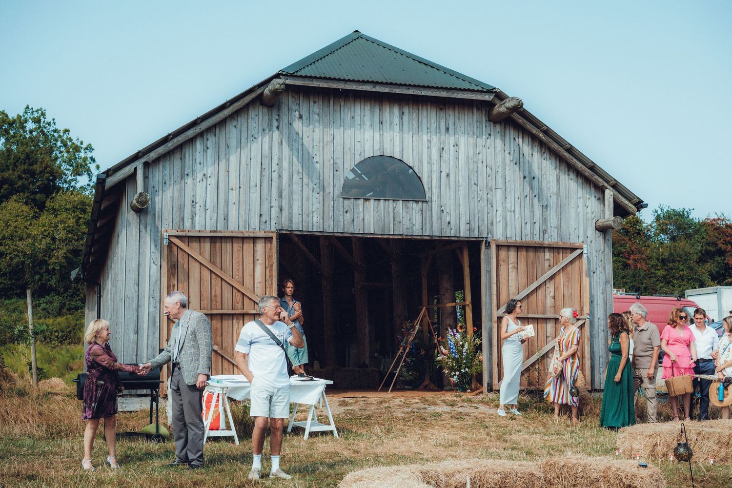 A rustic barn in a rural field with wooden doors and corrugated metal siding.