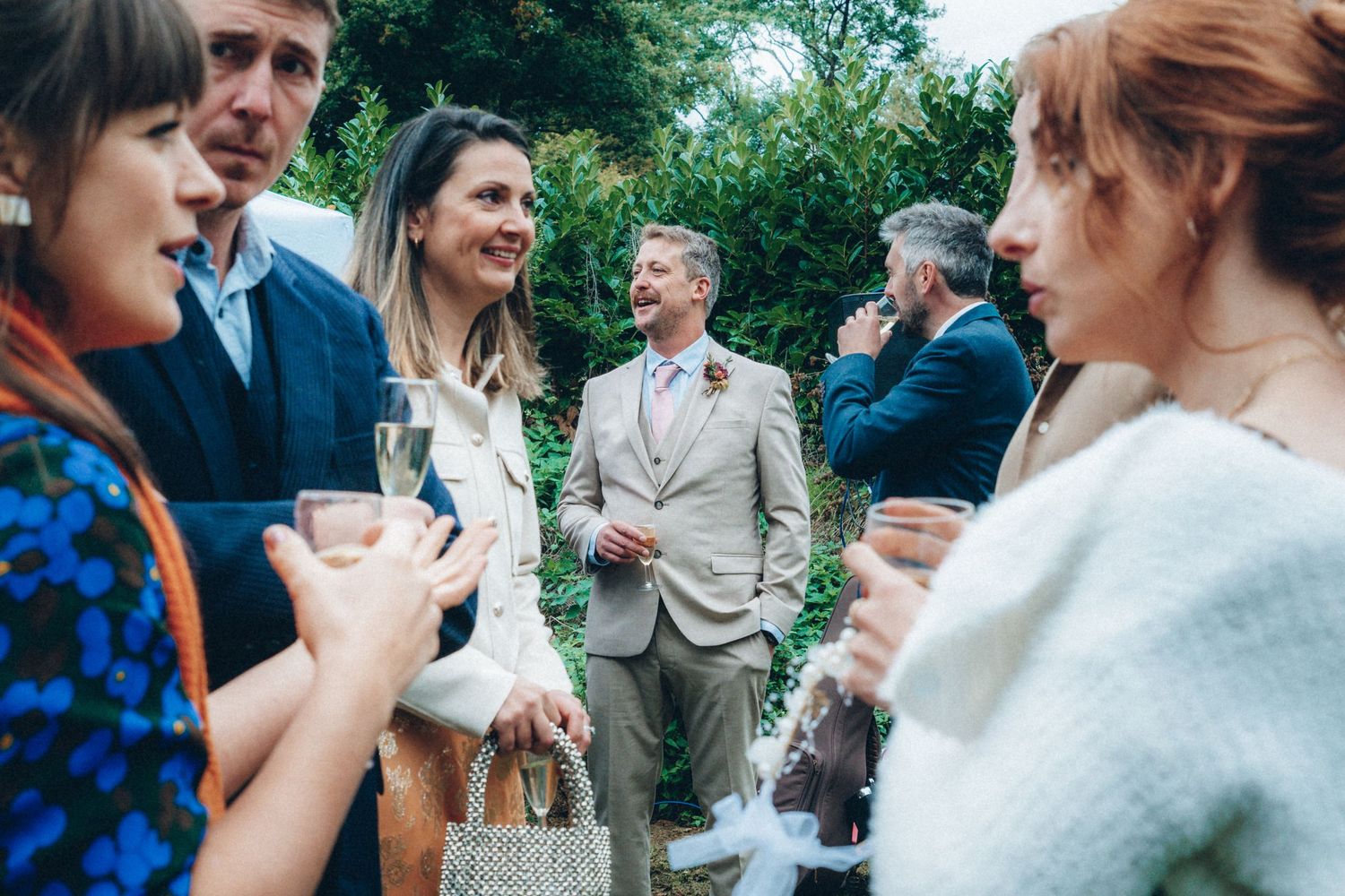 Wedding guests mingle and chat during an outdoor garden reception.