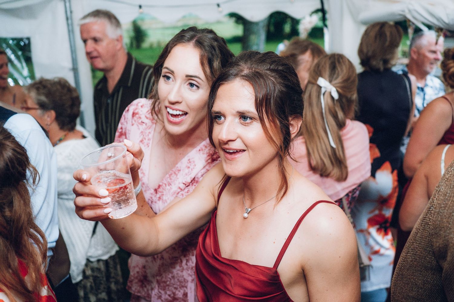 People enjoying drinks and laughing together at an outdoor celebration.