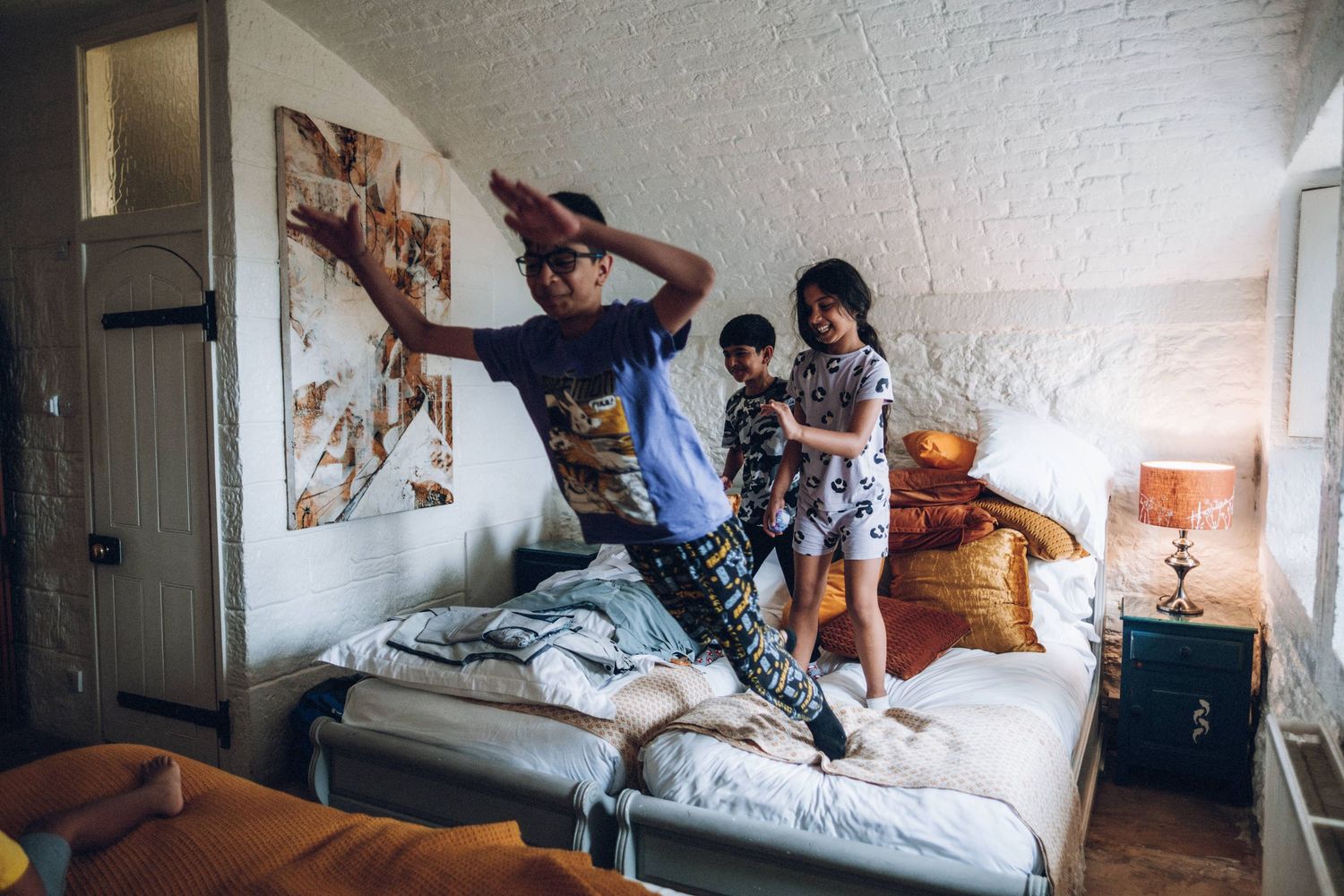 Group gathered on a bed in a sunlit room with white walls and casual atmosphere.