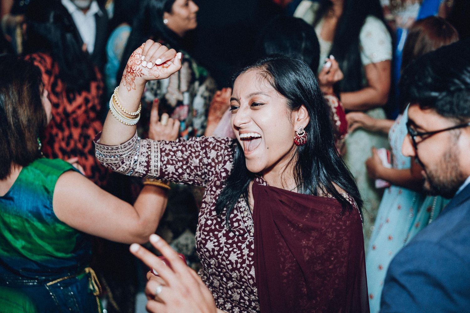 Wedding reception guest dancing enthusiastically among crowd of celebrants.