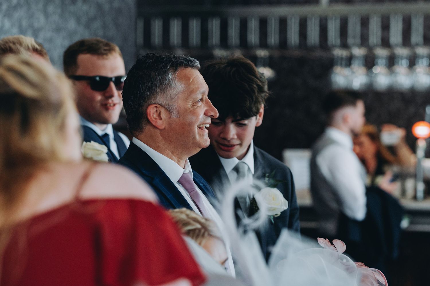A candid moment of laughter and smiles among formally dressed guests at an elegant wedding,