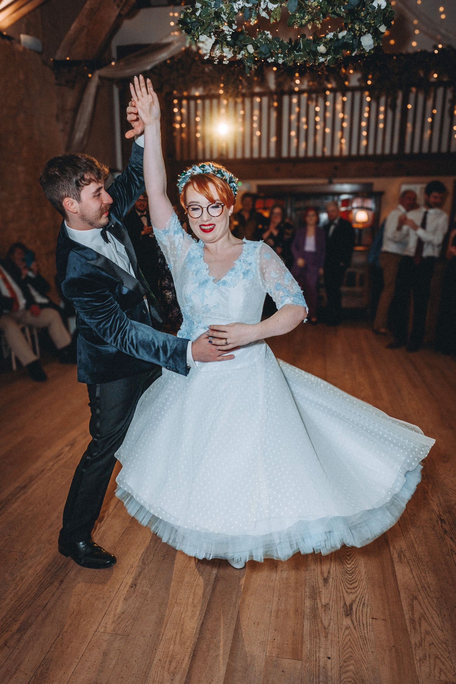 Couple dancing with joy on wooden floor during their wedding reception.