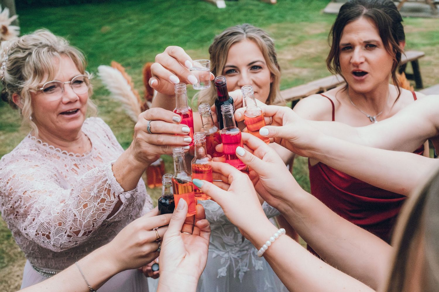 Wedding guests raise colorful cocktail glasses in a celebratory outdoor toast.