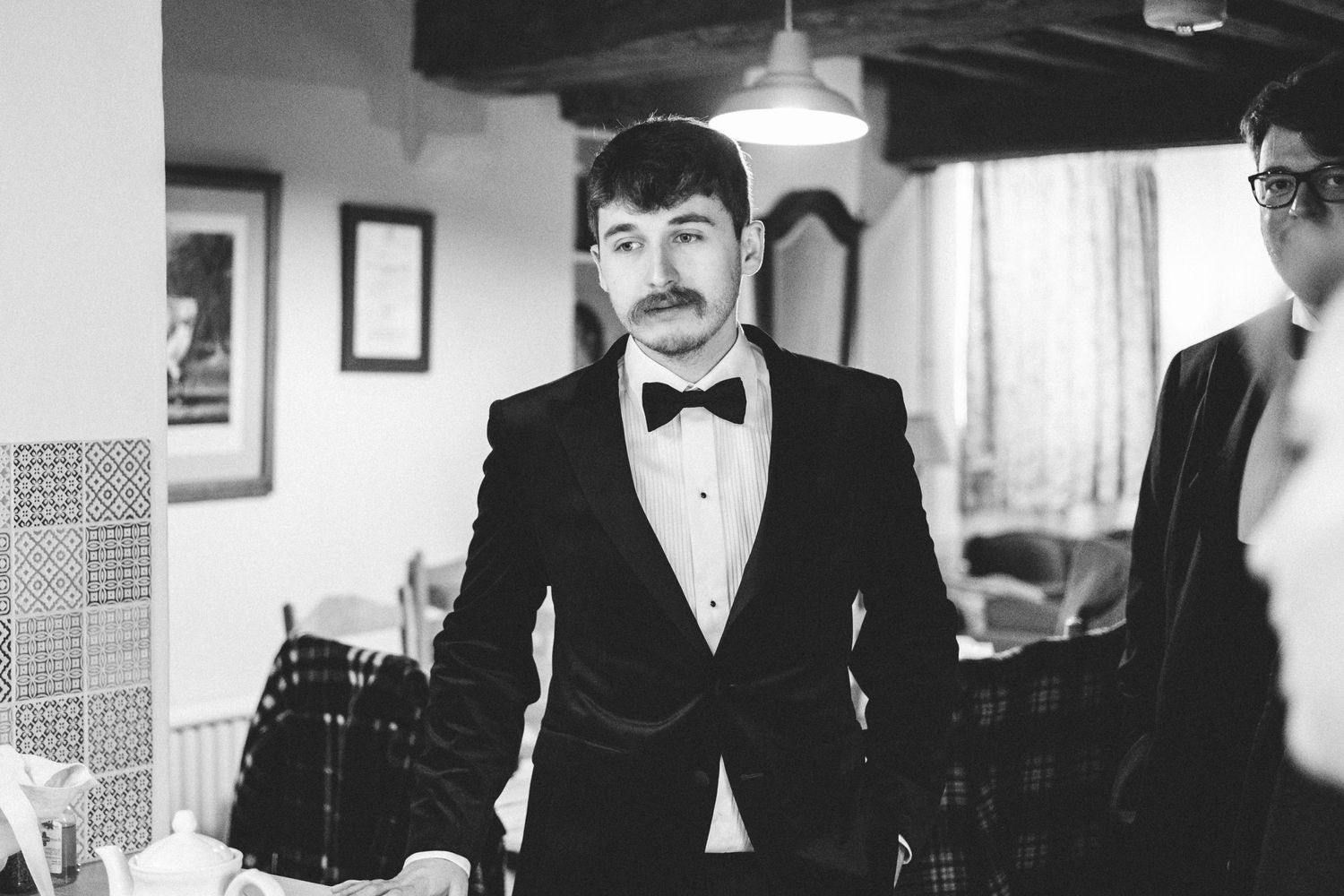 A well-dressed groom in a black tuxedo and bowtie patiently waiting for his wedding ceremony to commence.