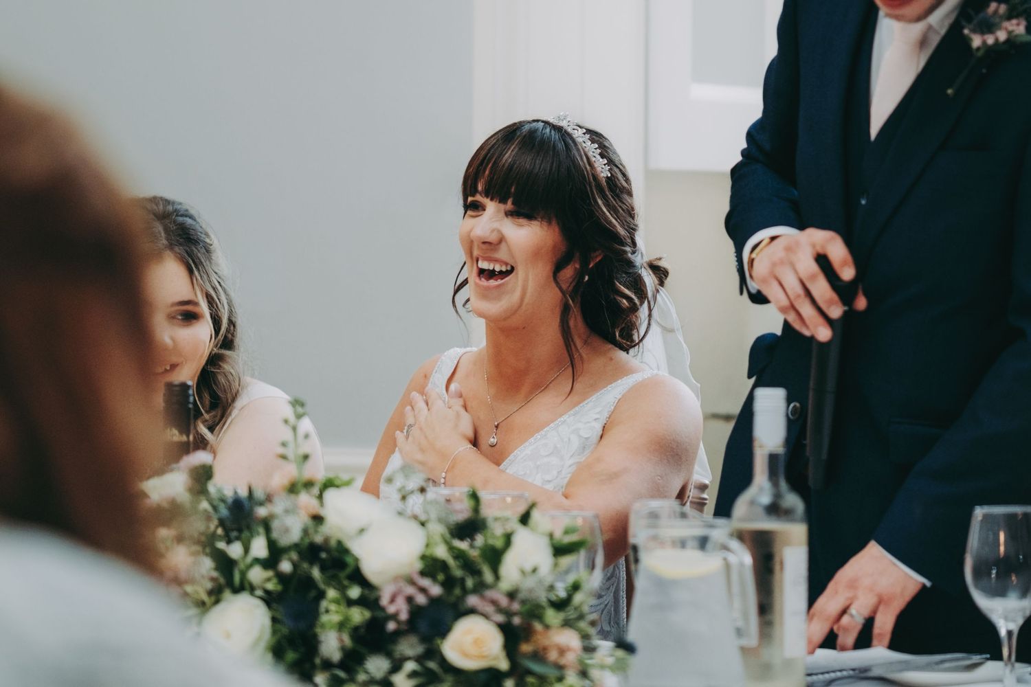 Candid moment of laughter during wedding reception with floral table decorations.