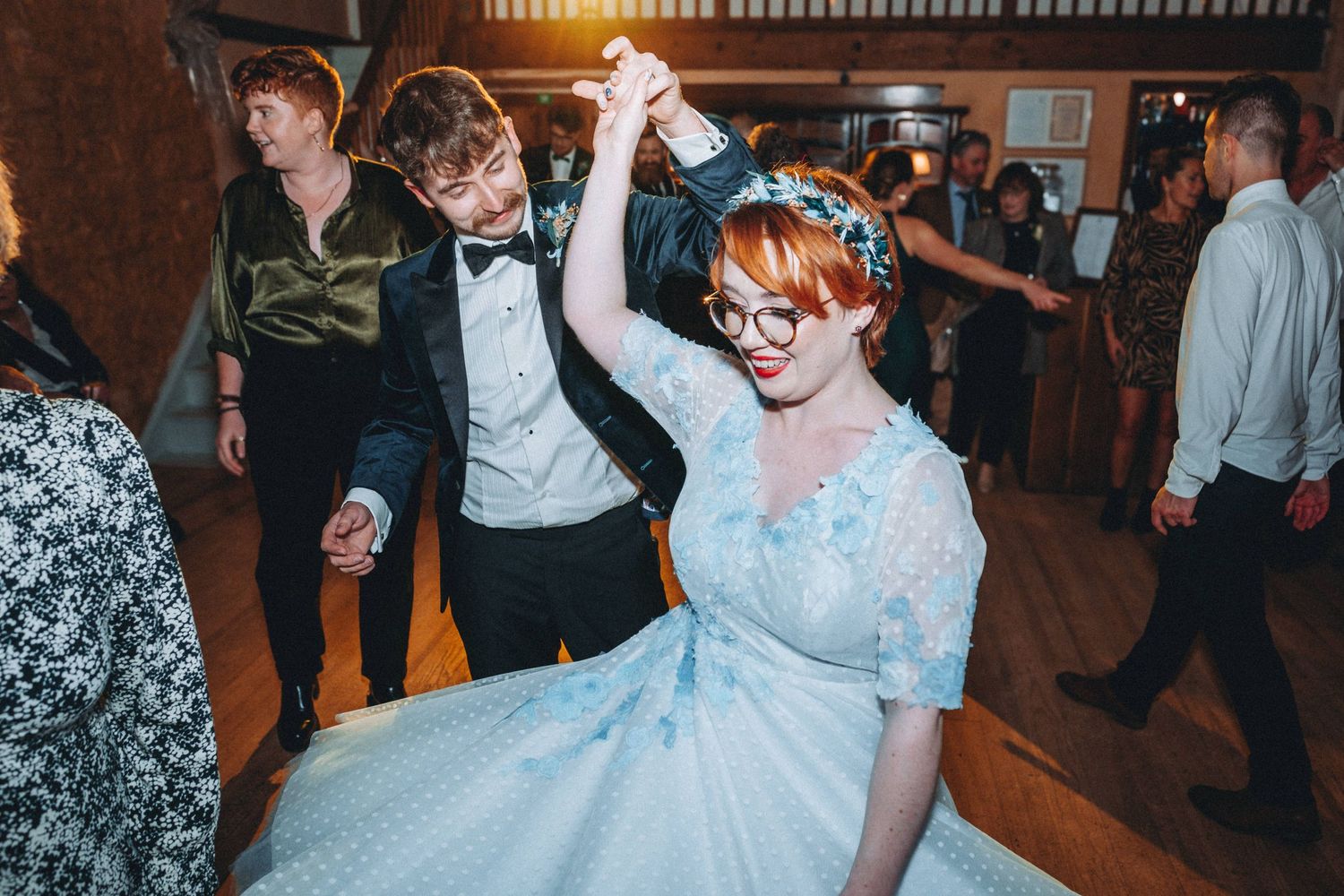 Dancing celebration at wedding reception with light blue dress twirling on dance floor.