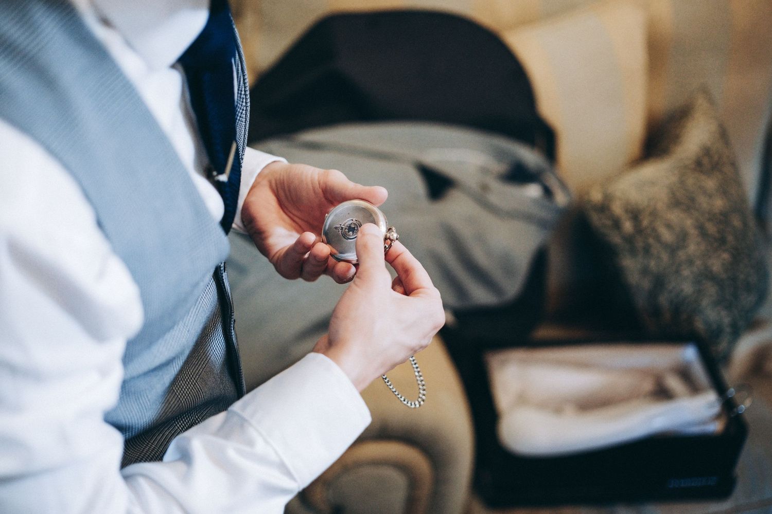 Close up shot of hands threading a needle with white thread against a blurry background.