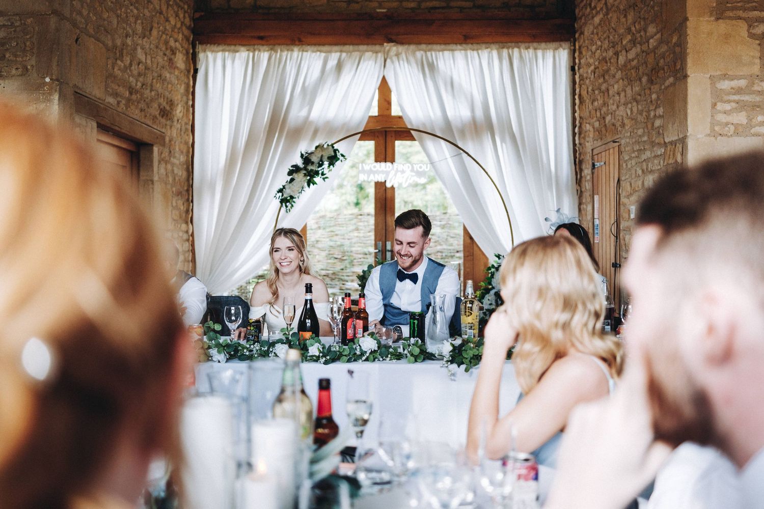 Wedding reception venue decorated with white drapes and stone walls creates romantic atmosphere.