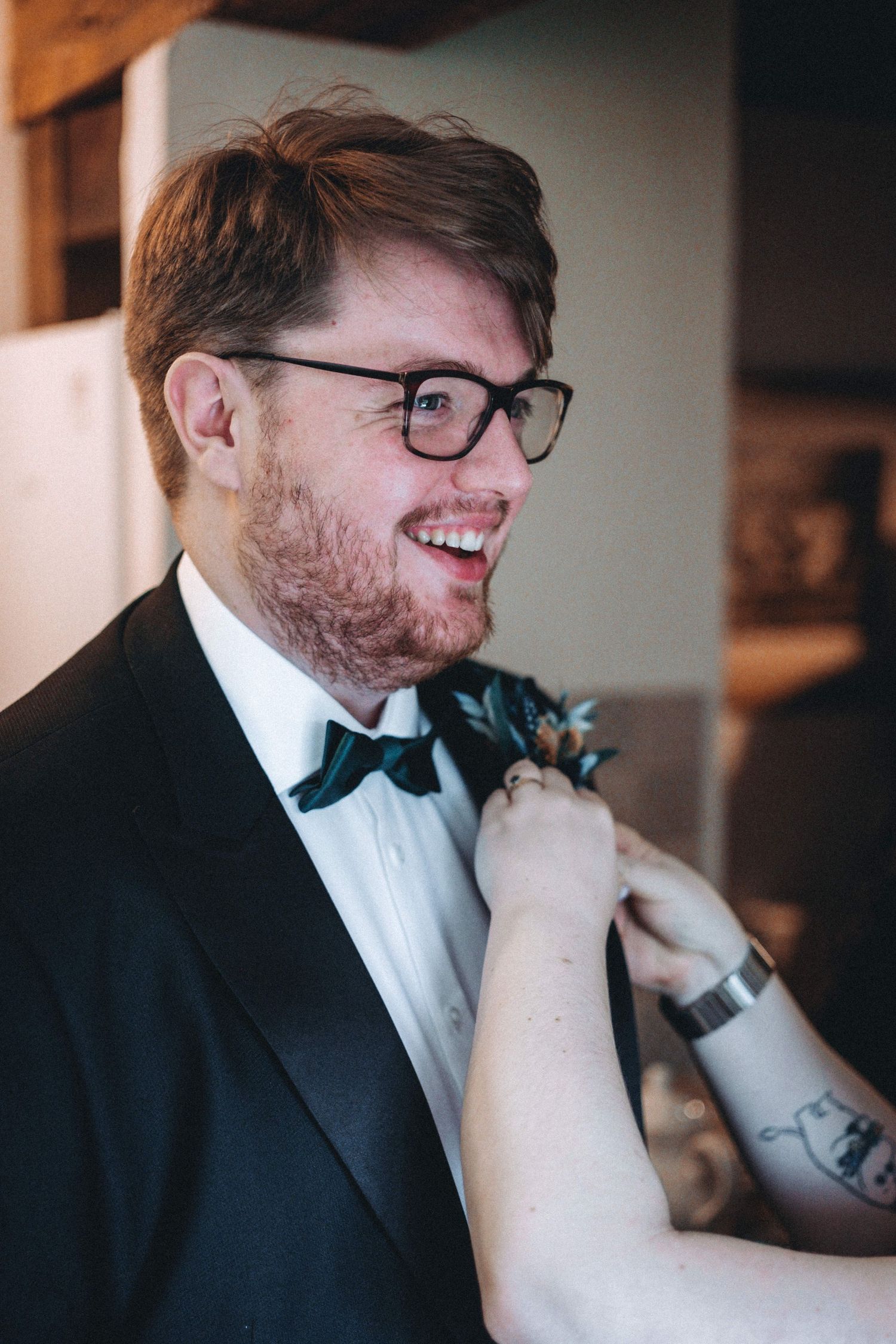 Formal attire preparation scene with bow tie and boutonniere adjustments.
