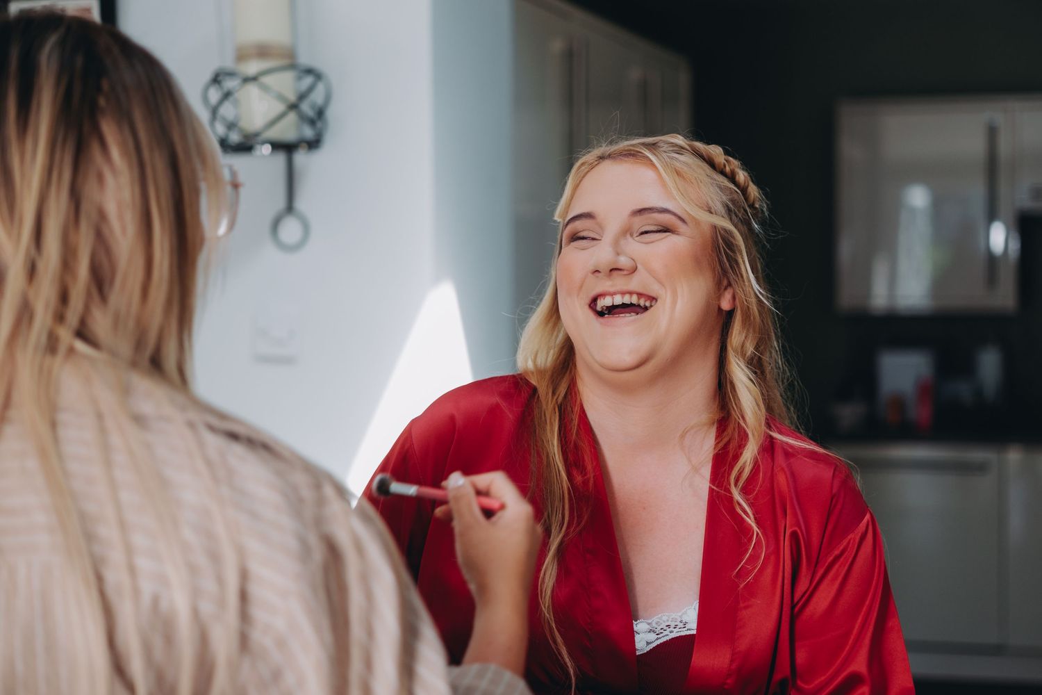 Candid moment of laughter during wedding morning preparations in a bright room.