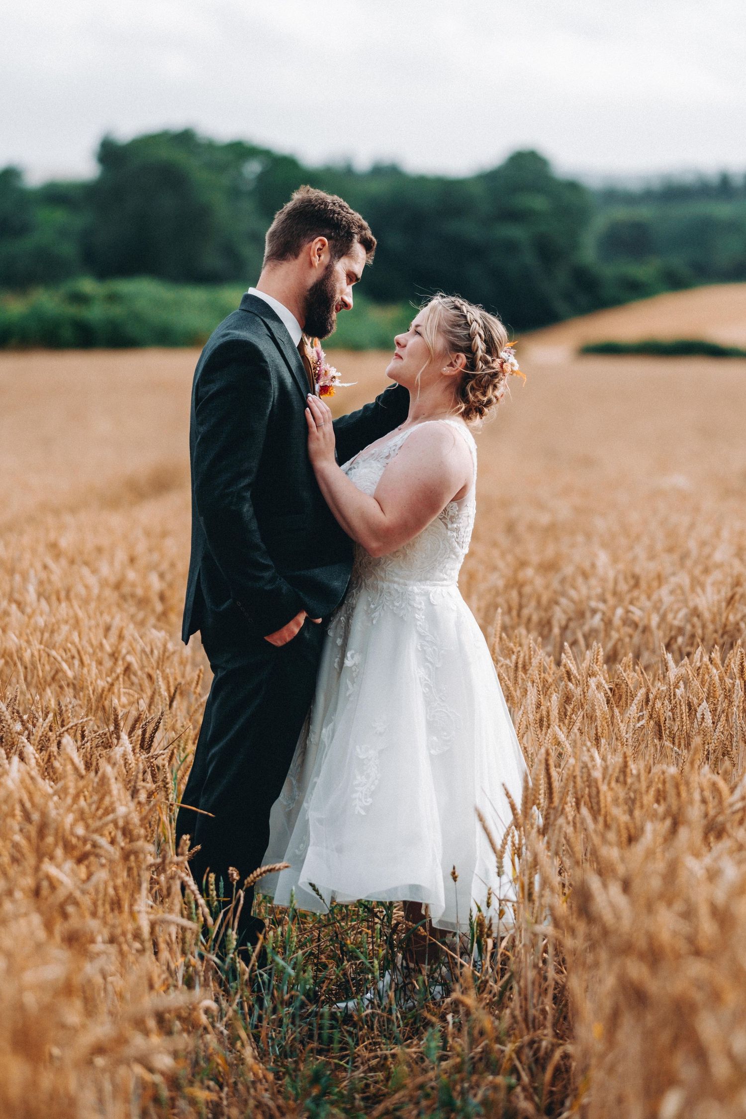 A joyful wedding couple embraces in a golden wheat field on their special day.