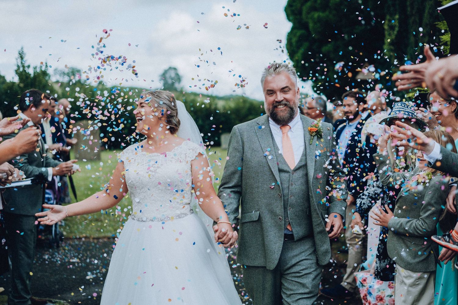 Wedding couple surrounded by confetti during an outdoor celebration.