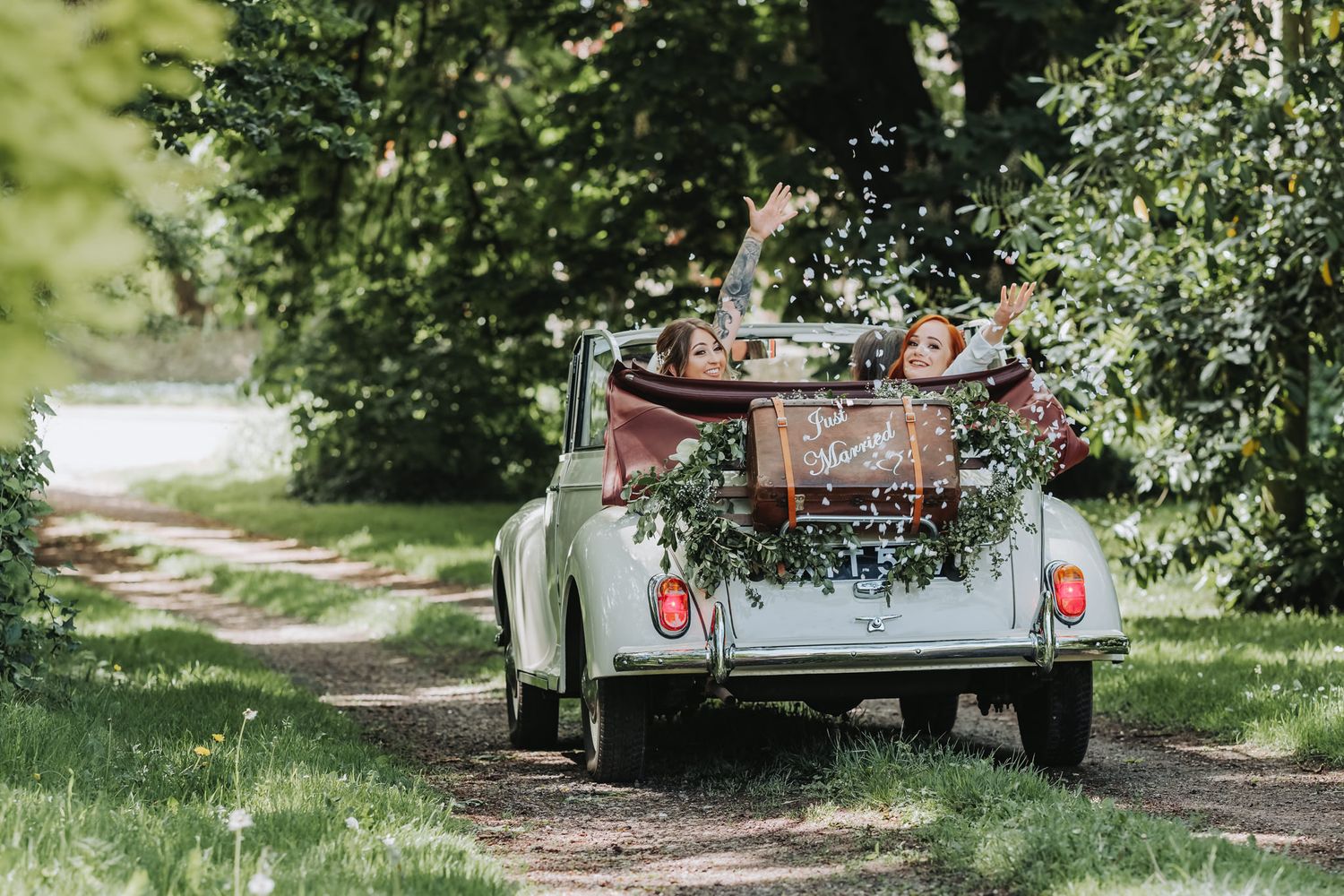 Rustic vintage trailer parked among green trees in a natural outdoor setting.