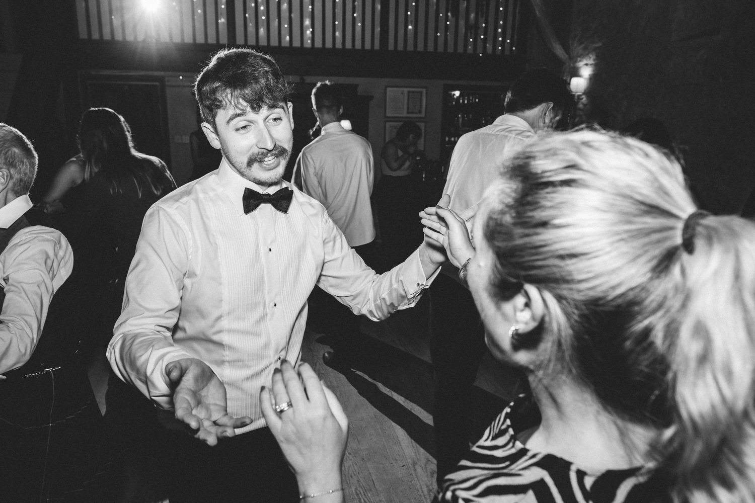 Black and white photo of guests dancing at wedding reception.