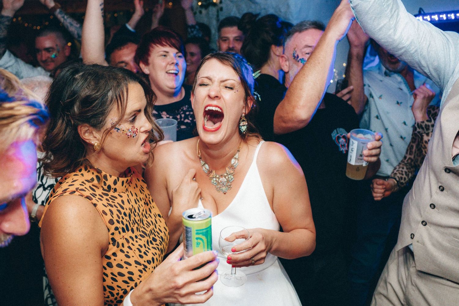 Energetic dance floor scene with guests celebrating at a wedding reception with leopard print accents.
