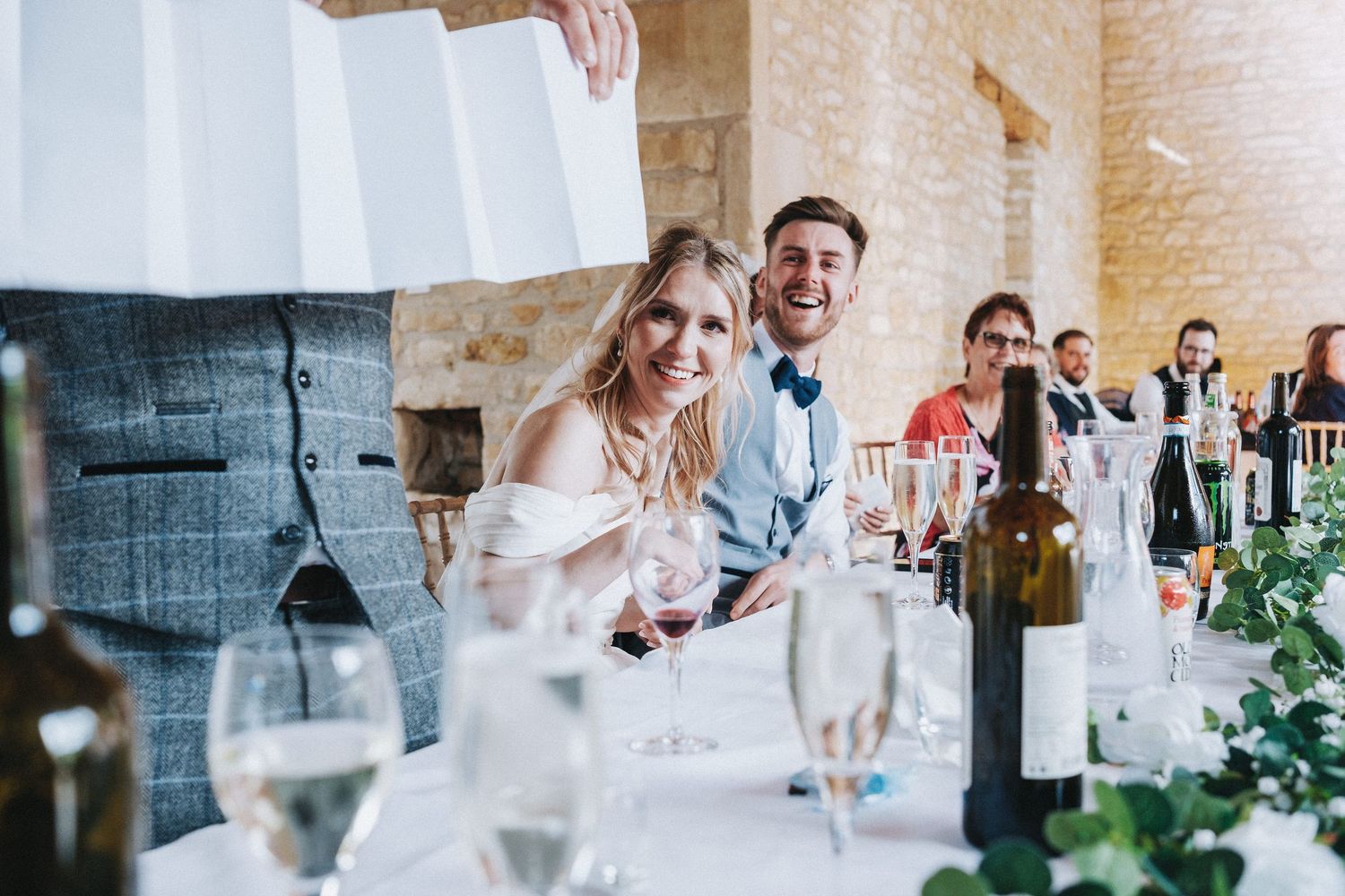 Wedding reception setup with elegant table settings and natural stone walls.