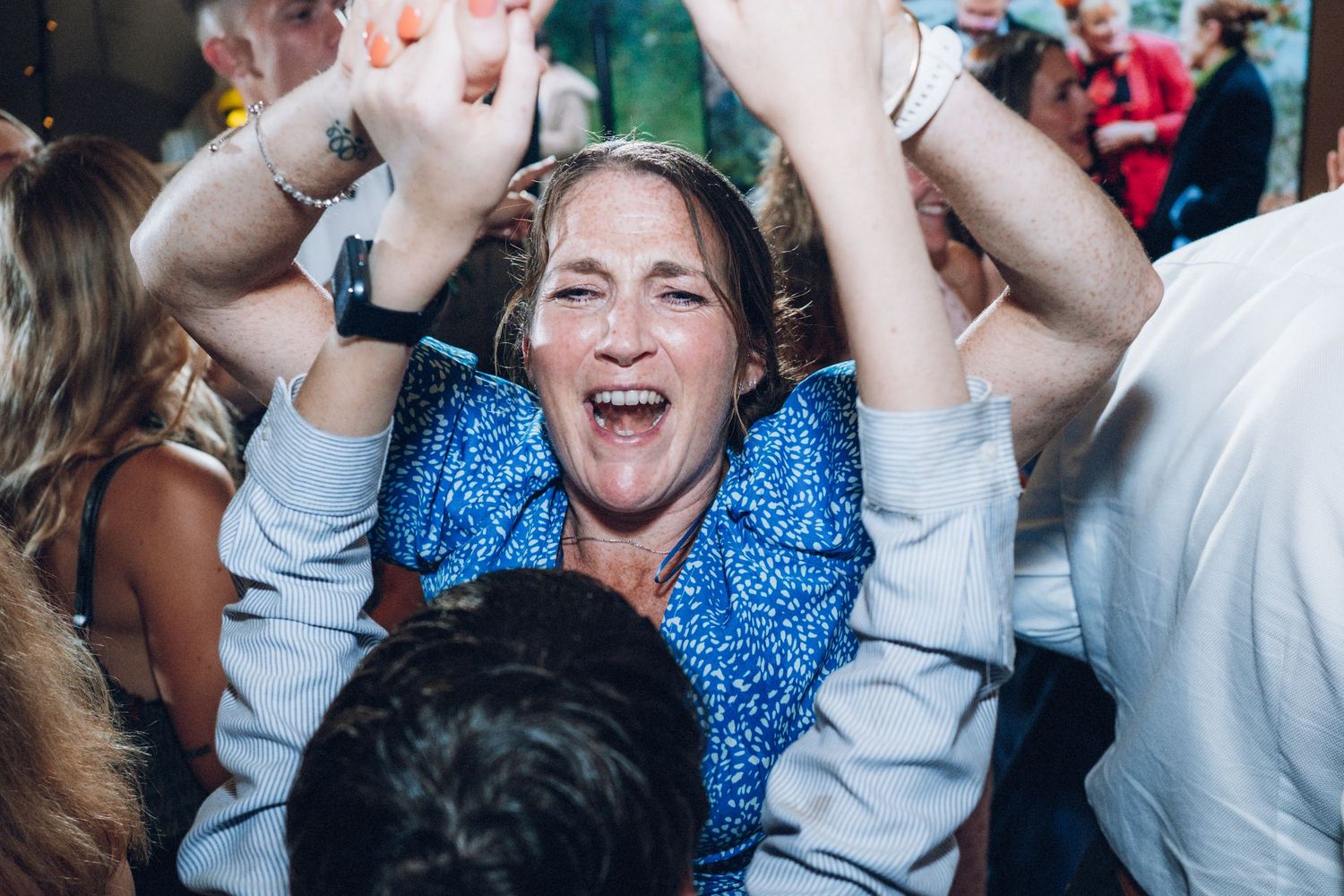 Energetic crowd dancing and laughing during a wedding celebration.
