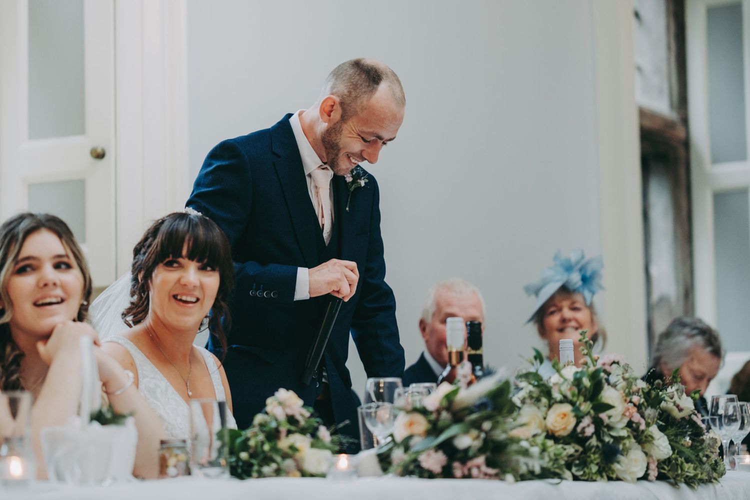 Candid reactions during wedding speeches at elegant reception dinner.
