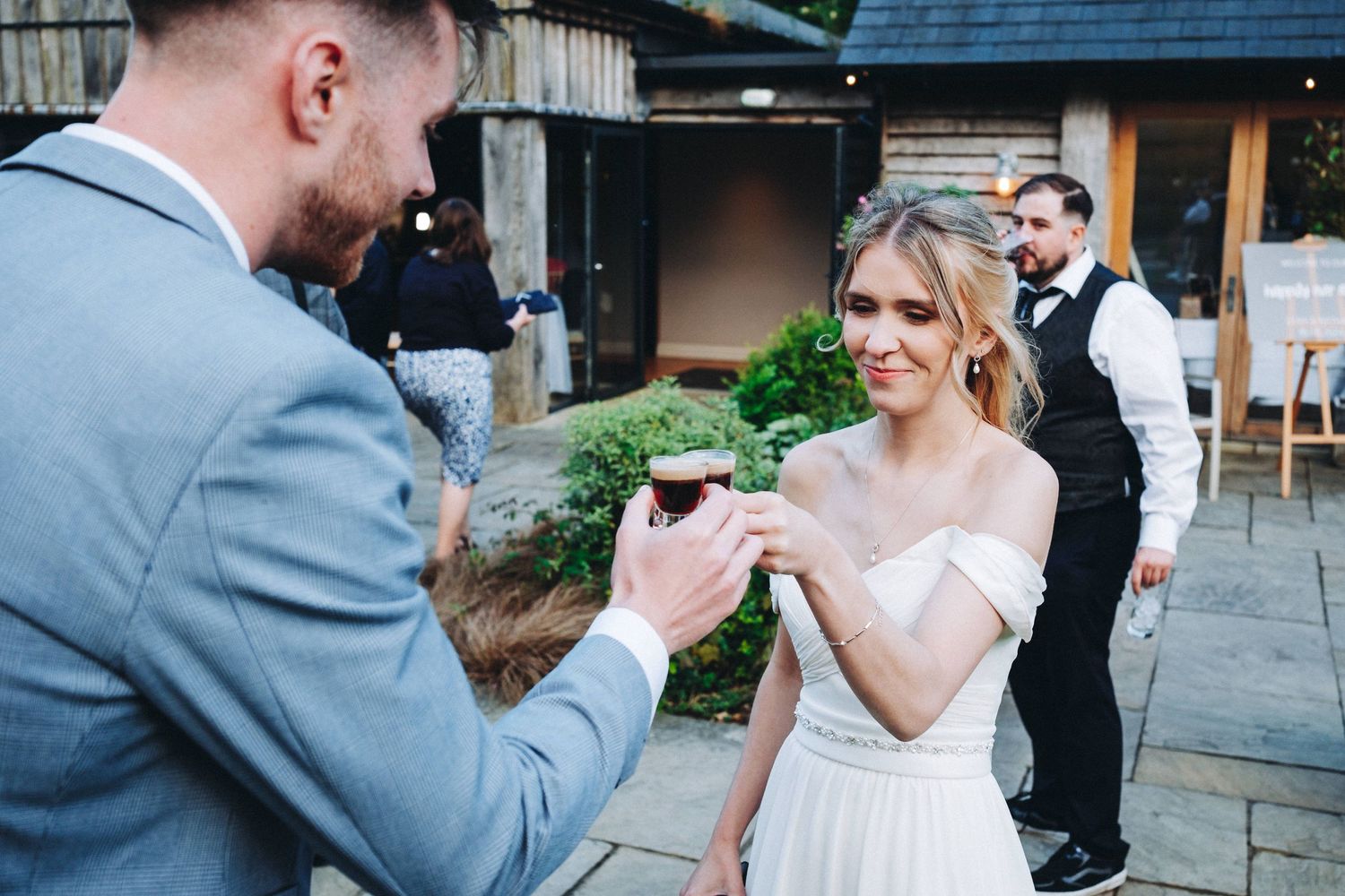 A couple in wedding attire shares a celebratory moment with beverages at an outdoor venue.