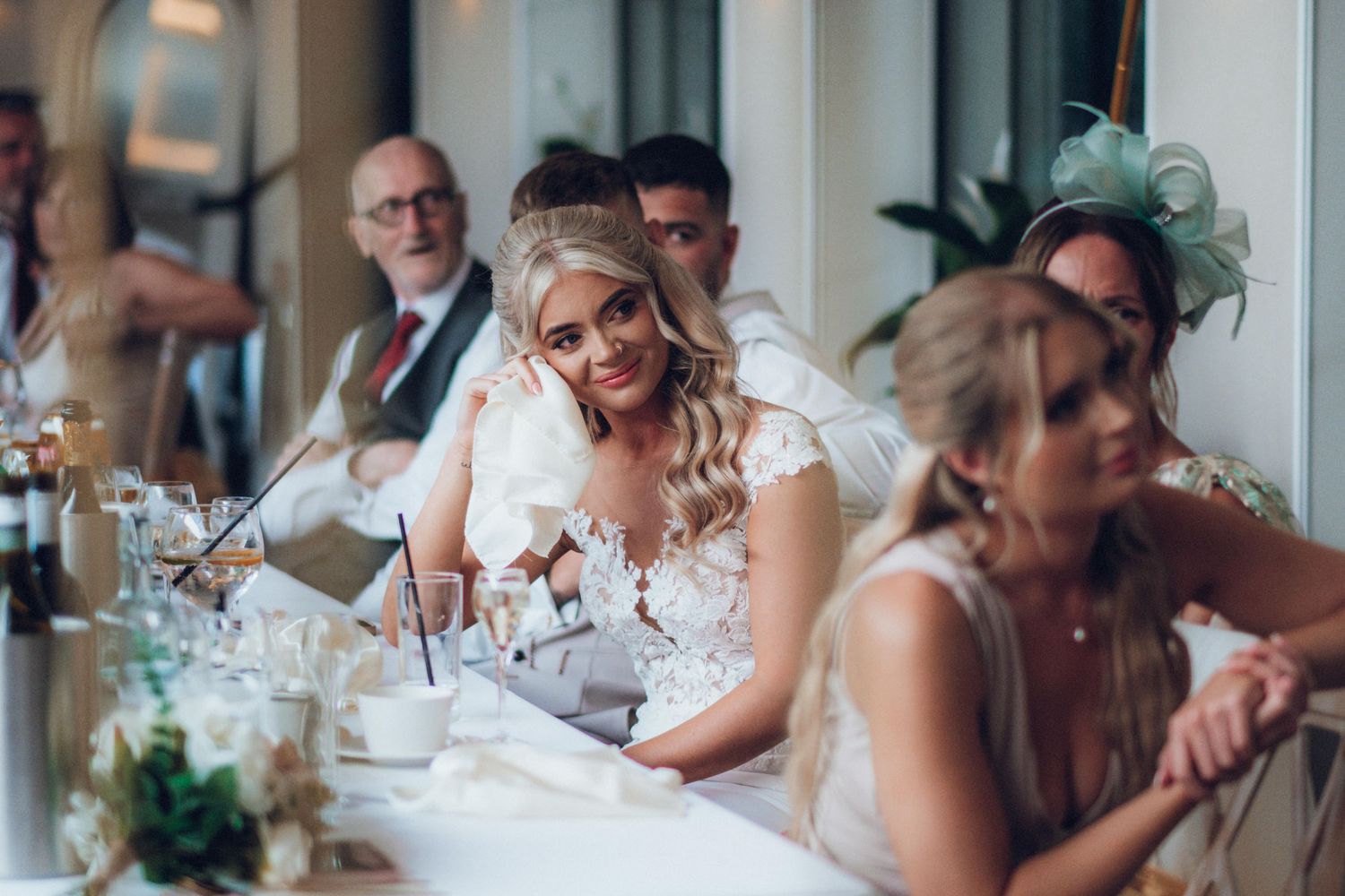 Wedding guests enjoying a reception dinner at an elegantly decorated table with floral centerpieces.