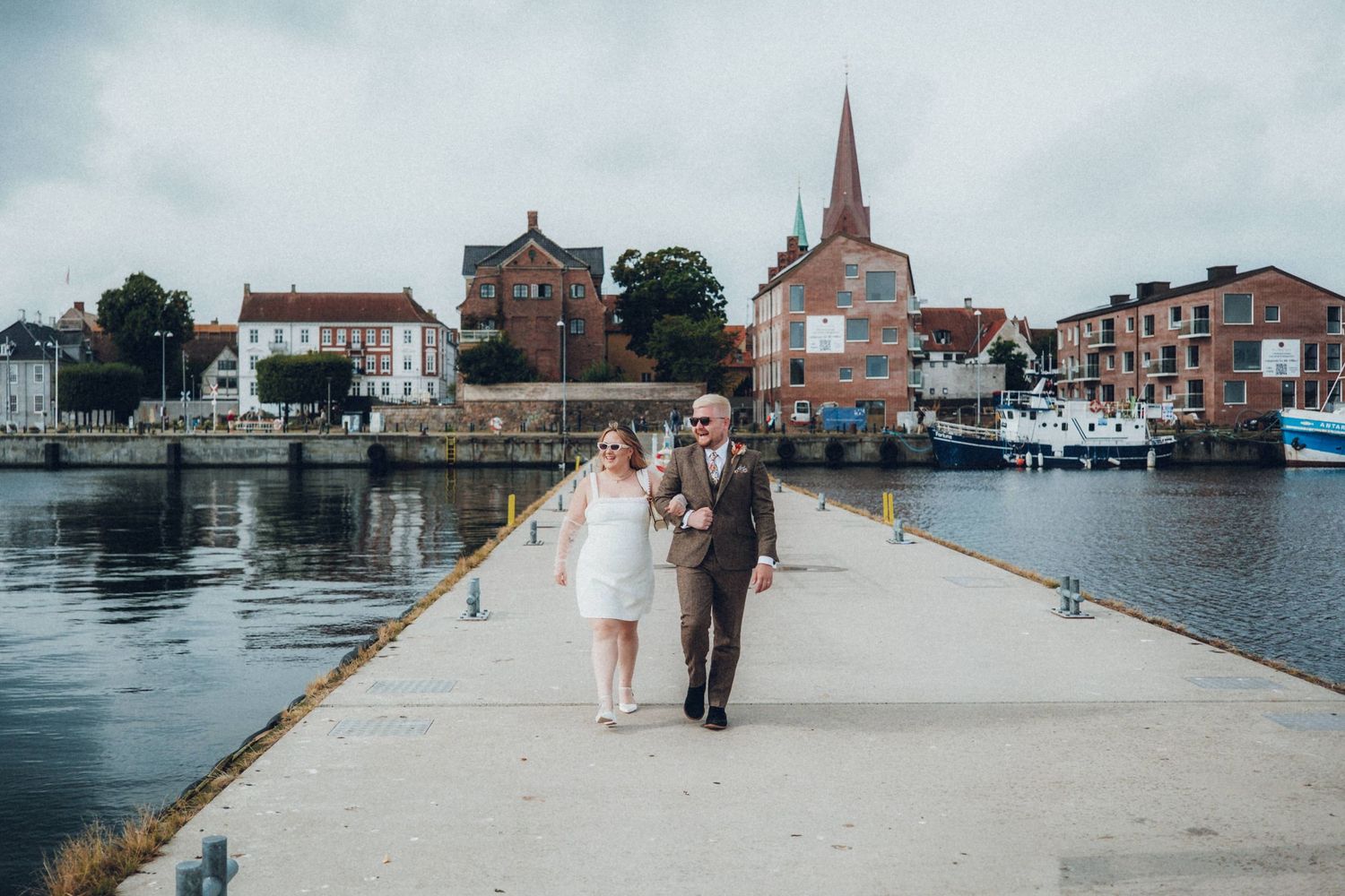Scenic waterfront promenade with historic buildings and church spire in background.