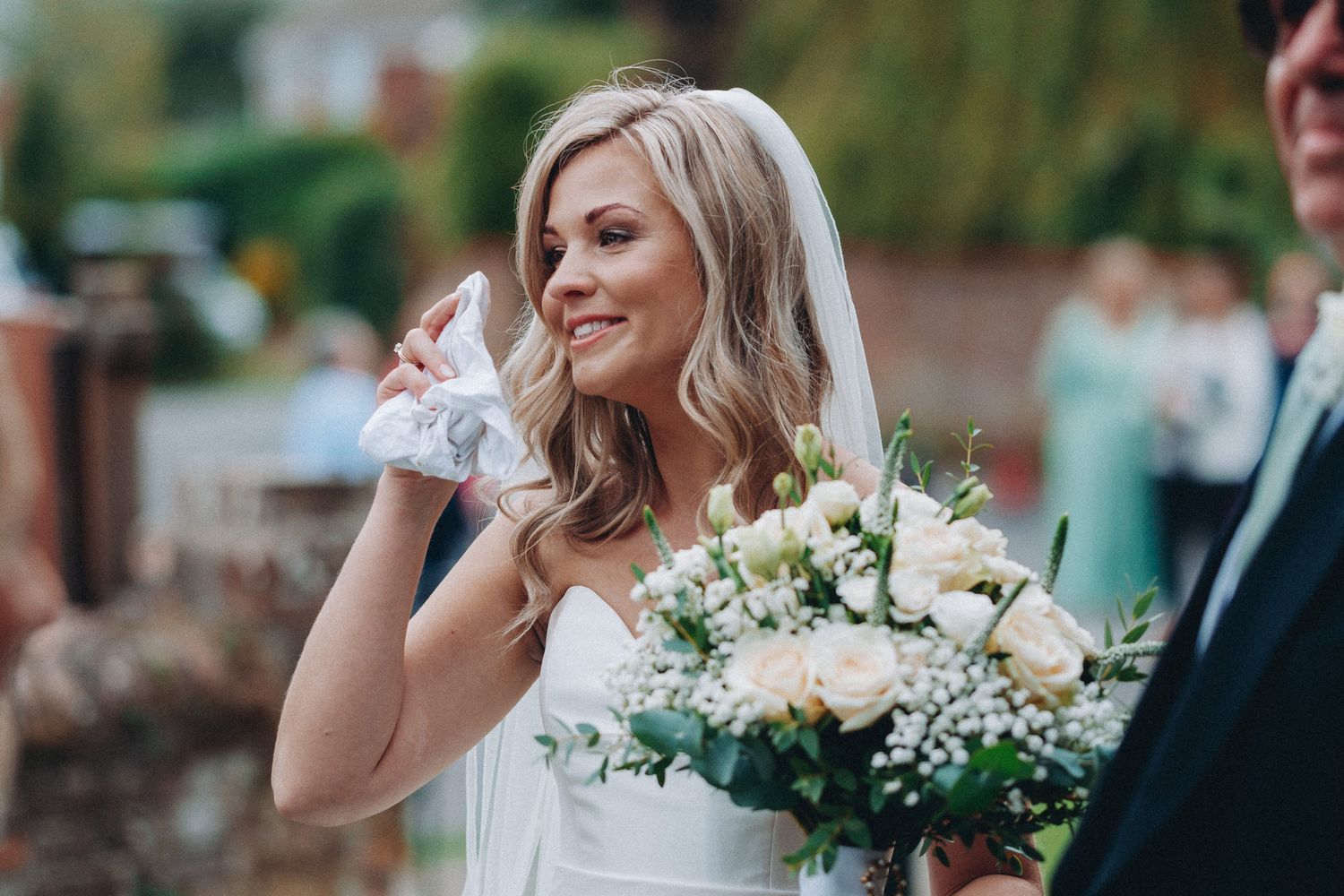 Wedding couple poses with elegant white floral bouquets outdoors.