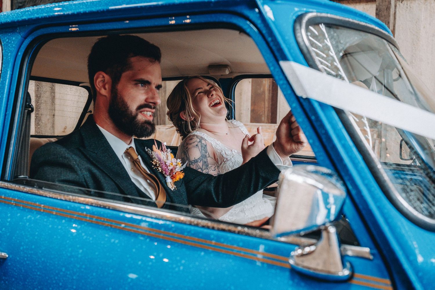 bride and groom sitting in a bright blue vintage mini enjoying a lively moment together.