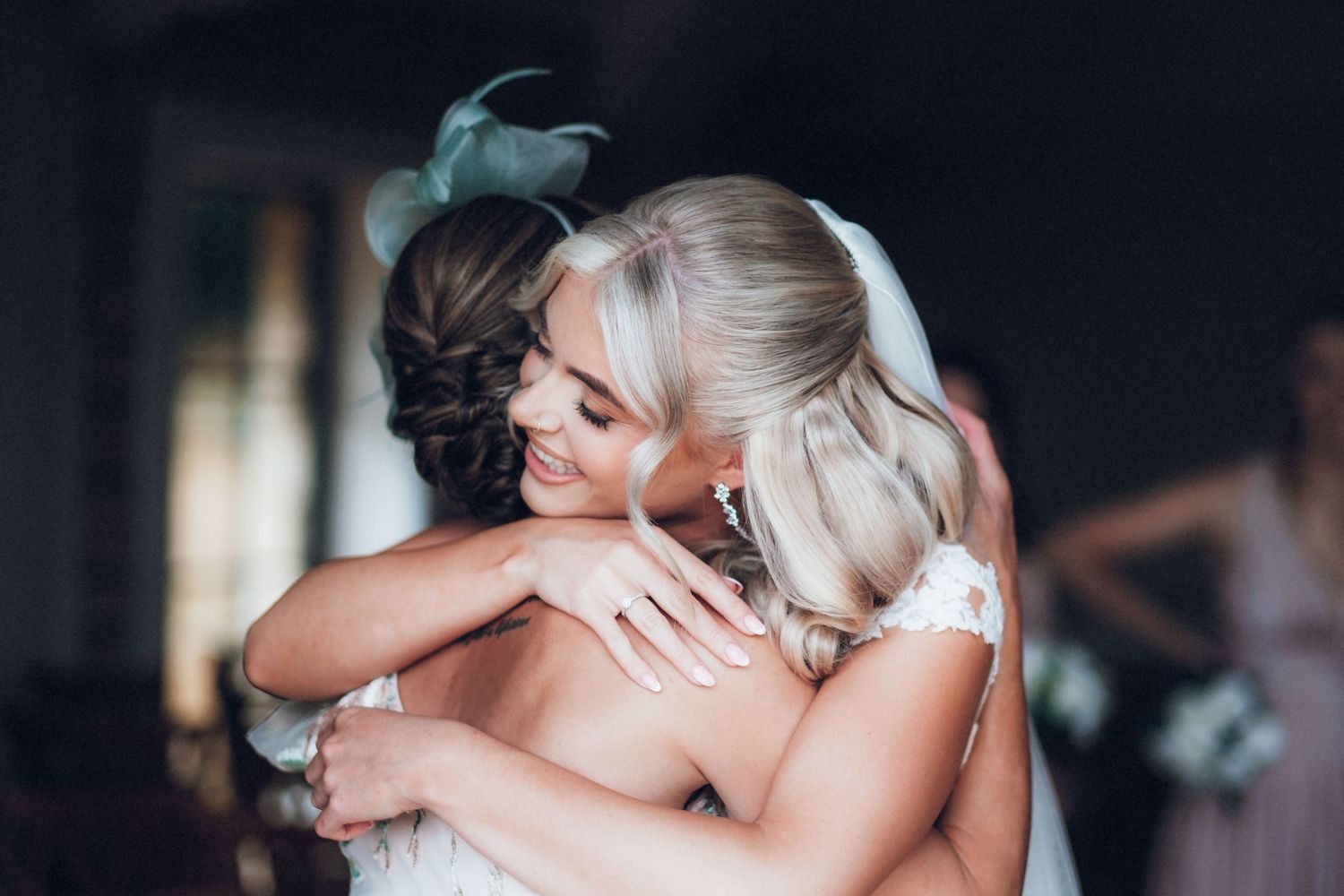 An emotional embrace shared during a wedding celebration in a dimly lit venue.