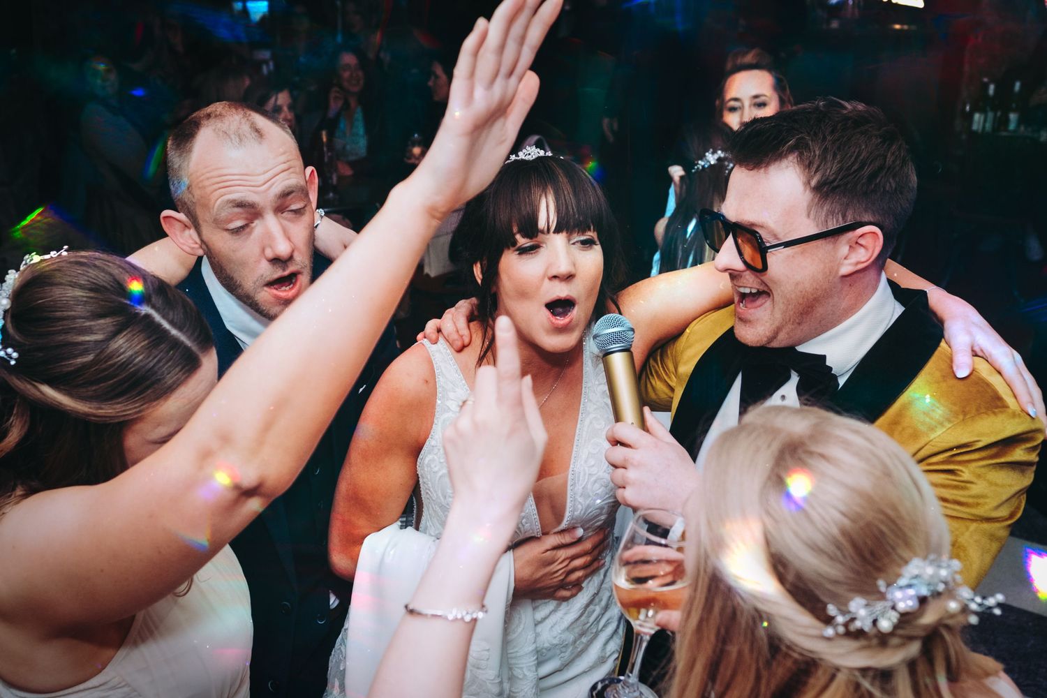 Lively dance floor moment during wedding reception with guests in festive celebration.