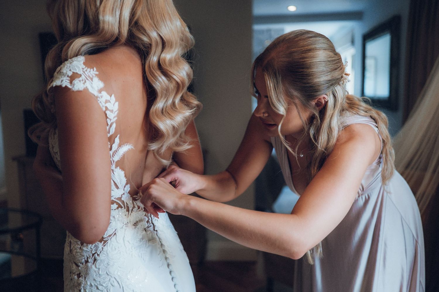 Close up details of delicate lace wedding dress being fastened.