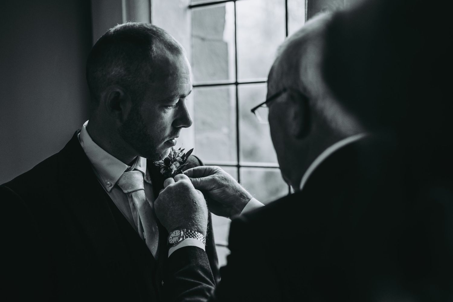 A black and white image of wedding preparation by a window.
