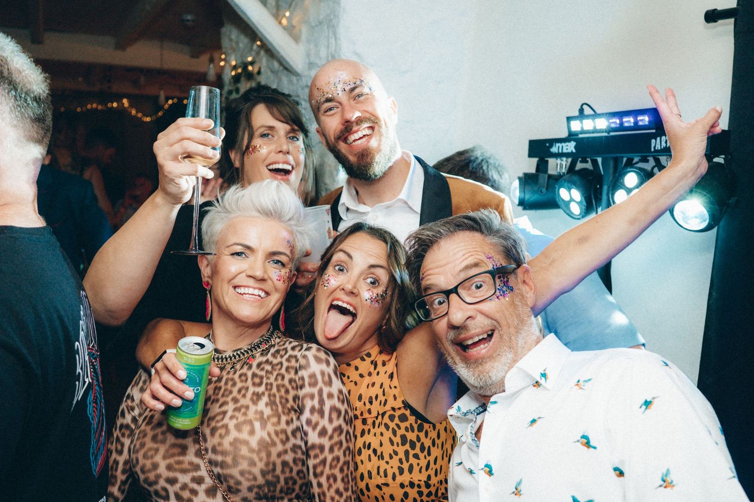 Guests laughing and embracing during an energetic celebration at an indoor venue.