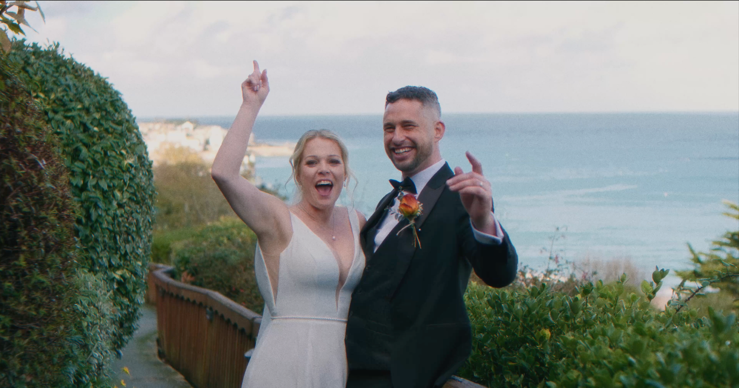 Wedding party celebrates outdoors with ocean views in the background.