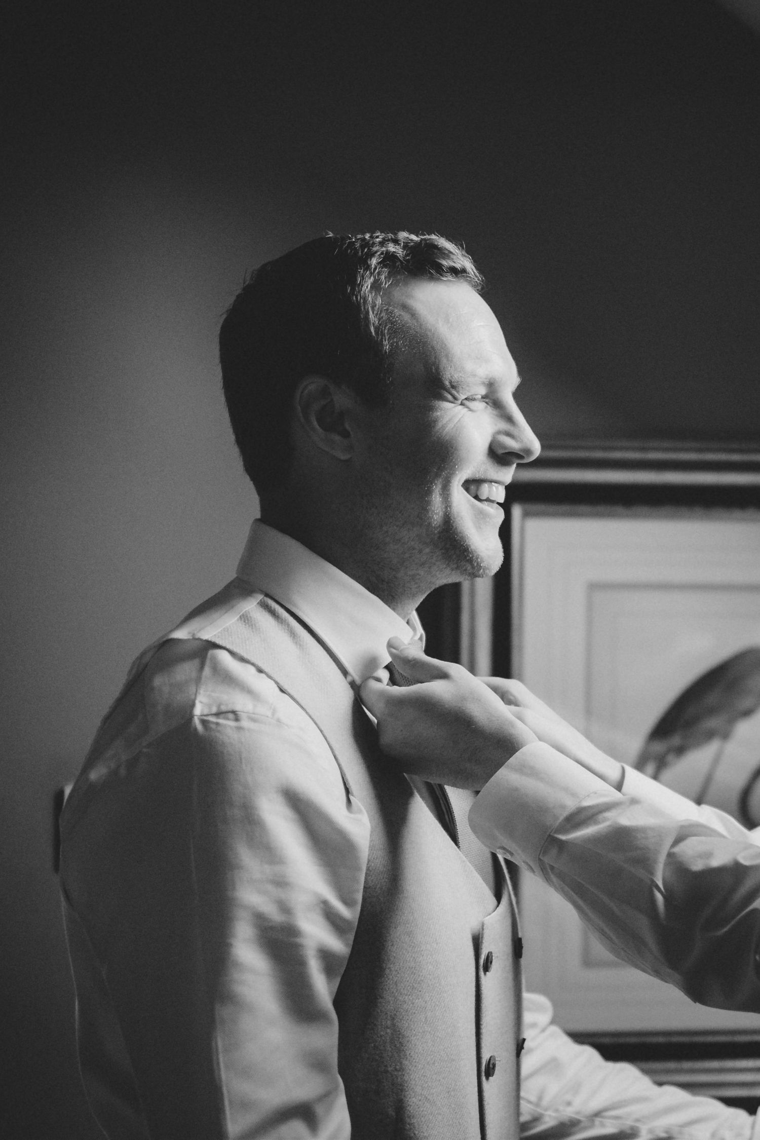 Black and white portrait of a smiling groom getting ready on his wedding day.